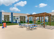 Thumbnail 9 of 23 - a picnic area with picnic tables and benches in front of a building