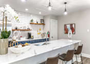 Thumbnail 2 of 23 - a kitchen with white countertops and a large white island with a sink and three chairs