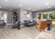 Thumbnail 19 of 34 - A living room with grey couches and wooden floors.