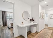 Thumbnail 11 of 45 - A white desk with a round mirror above it in a room.