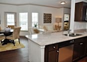 Thumbnail 11 of 33 - living room with wood floor and windows and kitchen with wood cabinets