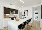 Thumbnail 1 of 29 - A modern kitchen with white countertops and black chairs.