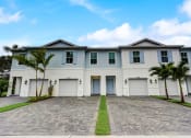 Thumbnail 3 of 30 - Boatman Hammock Townhomes in Lake Worth, FL photo of  a large white house with palm trees in front of it