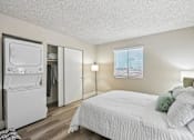 Thumbnail 27 of 34 - A white bedroom with a bed, a refrigerator, and a window with blinds.