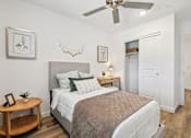 Thumbnail 20 of 45 - A bedroom with a bed, a ceiling fan, and a wooden side table.