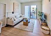 Thumbnail 6 of 36 - Bright living room at Gateway Luxury Apartments in Pompano Beach, featuring large sliding glass doors that open to a private balcony and fill the space with natural light.