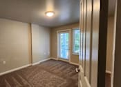 Thumbnail 5 of 16 - A room with a carpeted floor and a window with blinds.