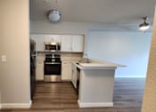 Thumbnail 6 of 16 - A kitchen with white cabinets and a black dishwasher.