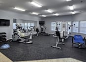 Thumbnail 11 of 17 - a gym with cardio equipment and a tv in a building