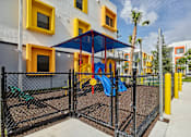 Thumbnail 22 of 36 - Playground area at Gateway Luxury Apartments in Pompano Beach, featuring modern play structures and a landscaped setting.