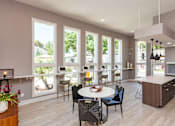 Thumbnail 14 of 34 - A modern kitchen with a dining table and chairs in the foreground and a balcony with a view of trees and a house in the background.
