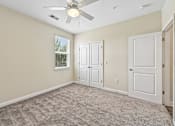 Thumbnail 16 of 48 - A bright Hawks Landing bedroom in Hickory NC featuring a ceiling fan and carpeted flooring