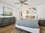 Thumbnail 12 of 45 - A bedroom with a bed, dresser, and ceiling fan.