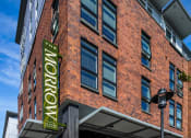 Thumbnail 1 of 50 - 1 BR Apartments In Greenwood, WA - The Morrow - Exterior View Of Property With Brick Details and Many Windows