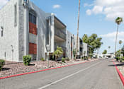 Thumbnail 25 of 34 - A street view of a row of modern buildings with palm trees on the side.