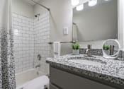 Thumbnail 11 of 20 - Bathroom at Idlewild 45 Apartments featuring granite vanity, modern fixtures, and tub-shower combination