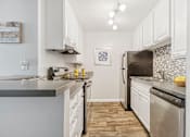 Thumbnail 2 of 32 - A kitchen with white cabinets and a tile backsplash.