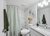 Thumbnail 31 of 34 - A bathroom with a toilet, sink, and shower curtain.