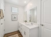 Thumbnail 23 of 45 - A white bathroom with a sink, mirror, and a rug on the floor.