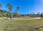 Thumbnail 53 of 56 - a park with a bench and a trash can in the middle of a grassy area