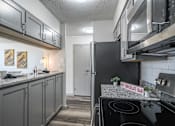 Thumbnail 6 of 20 - Modern kitchen at Idlewild 45 Apartments with stainless steel refrigerator, microwave, and granite countertops