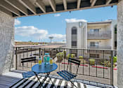 Thumbnail 24 of 34 - A balcony with a table and chairs overlooking a building.