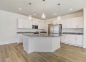 Thumbnail 14 of 20 - a kitchen with white cabinets and a large island with granite countertops