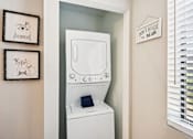 Thumbnail 17 of 46 - A white washing machine is in a small laundry room with a sign that says "Don't Make the Bear Sad" on the wall.