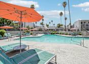 Thumbnail 16 of 34 - A pool area with a large orange umbrella and lounge chairs.