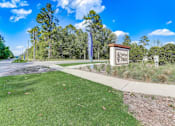 Thumbnail 50 of 56 - a park with a sign and trees in the background