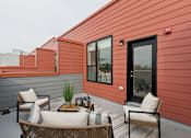 Thumbnail 9 of 65 - A patio with a table and chairs is on a red building.