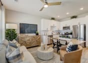 Thumbnail 11 of 56 - a living room and kitchen with white cabinets and a large tv on the wall