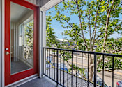 Thumbnail 14 of 24 - A red door is open to a balcony with a black railing.