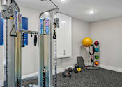 Thumbnail 22 of 34 - A gym room with a weight machine, dumbbells, and a ball.