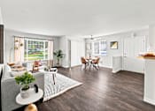 Thumbnail 1 of 47 - A living room with a grey sofa, a coffee table, a dining table with chairs, and a kitchen area with a countertop.
