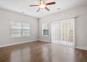 Thumbnail 11 of 26 - Harris Trail Luxury Townhomes for rent Richmond Hill, GA photo of an empty living room with a ceiling fan and a window