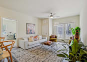 Thumbnail 7 of 39 - A living room with a white couch, a rug, and a ceiling fan.