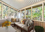 Thumbnail 11 of 16 - Greentree Apartments in Savannah, GA photo of a screened porch with a couch and a table with flowers