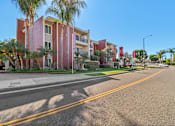 Thumbnail 30 of 32 - A street view of a residential area with apartment buildings and palm trees.