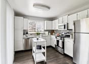 Thumbnail 1 of 15 - Open-concept kitchen with white cabinets and stainless steel fridge at Ashford at Geneva – pet-friendly apartments in Geneva, IL