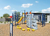 Thumbnail 36 of 45 - A playground with a blue and yellow slide and climbing structure.