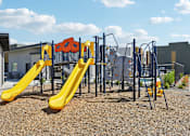 Thumbnail 37 of 45 - A playground with a yellow slide and a blue and yellow climbing frame.