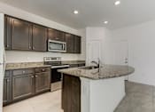 Thumbnail 45 of 56 - a kitchen with brown cabinets and a granite counter top