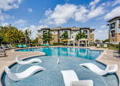 Thumbnail 2 of 16 - Resort-style swimming pool with in-water tanning loungers at 33hundred Apartments on Wells Branch Parkway Austin TX, offering luxury amenities and pet-friendly living