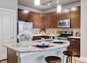 Thumbnail 1 of 16 - Modern upgraded kitchen at 33hundred Apartments in Austin TX with stainless steel appliances, granite countertops, and wood-style flooring in pet-friendly 1, 2, and 3 bedroom homes