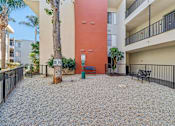 Thumbnail 29 of 32 - A courtyard with a red wall and a tree in the middle.