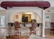 Thumbnail 13 of 15 - Derby Park Apartments in Daytona Beach, FL photo of a kitchen with a bar and two chairs in the clubhouse
