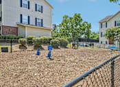 Thumbnail 27 of 34 - A playground with a blue slide and a fence in front of apartment buildings.