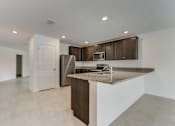 Thumbnail 44 of 56 - a kitchen with an island with granite countertops and a stainless steel refrigerator