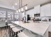 Thumbnail 8 of 47 - A kitchen with white cabinets and a long island with bar stools.